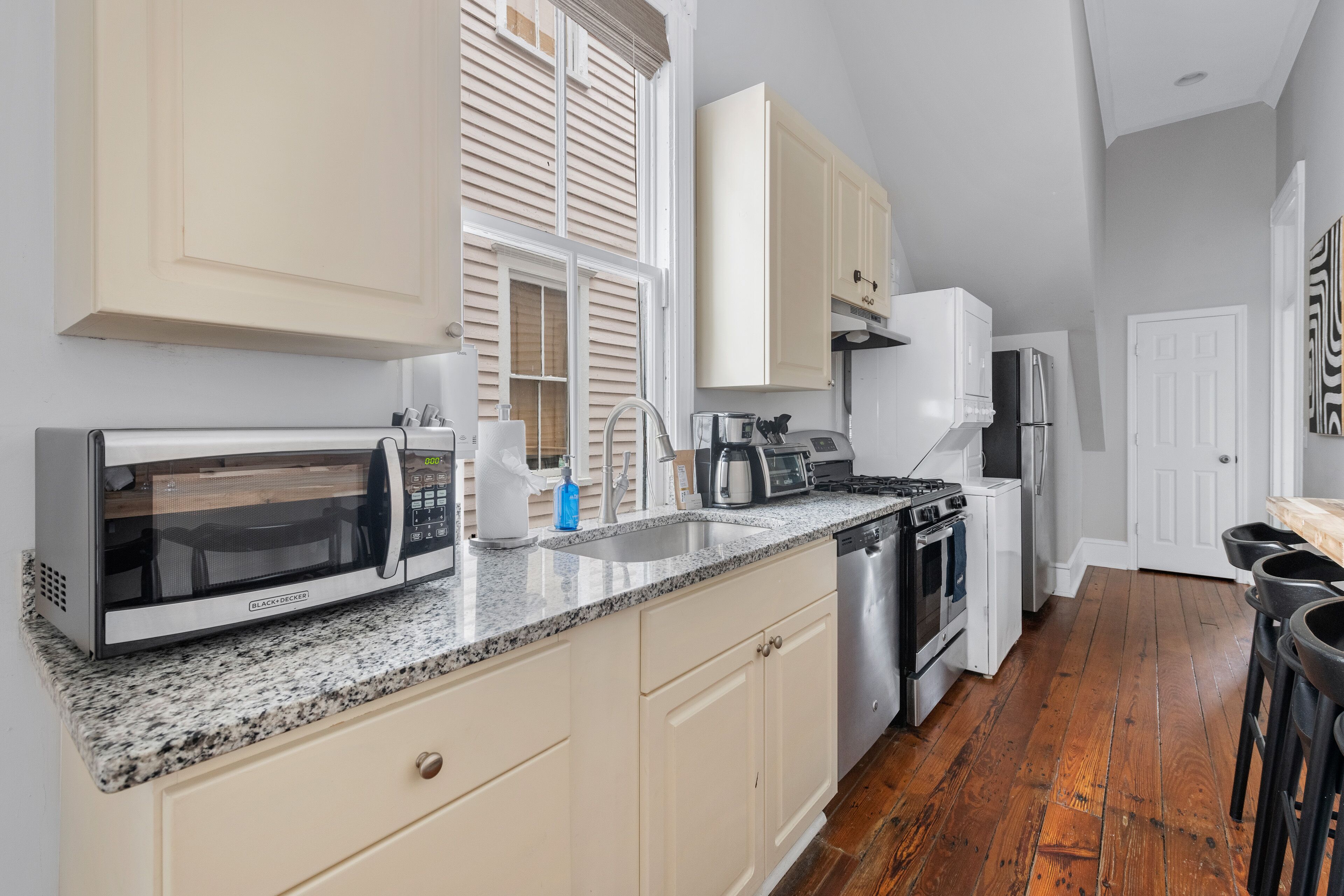 A kitchen with a microwave, toaster, sink, and stainless steel appliances.
