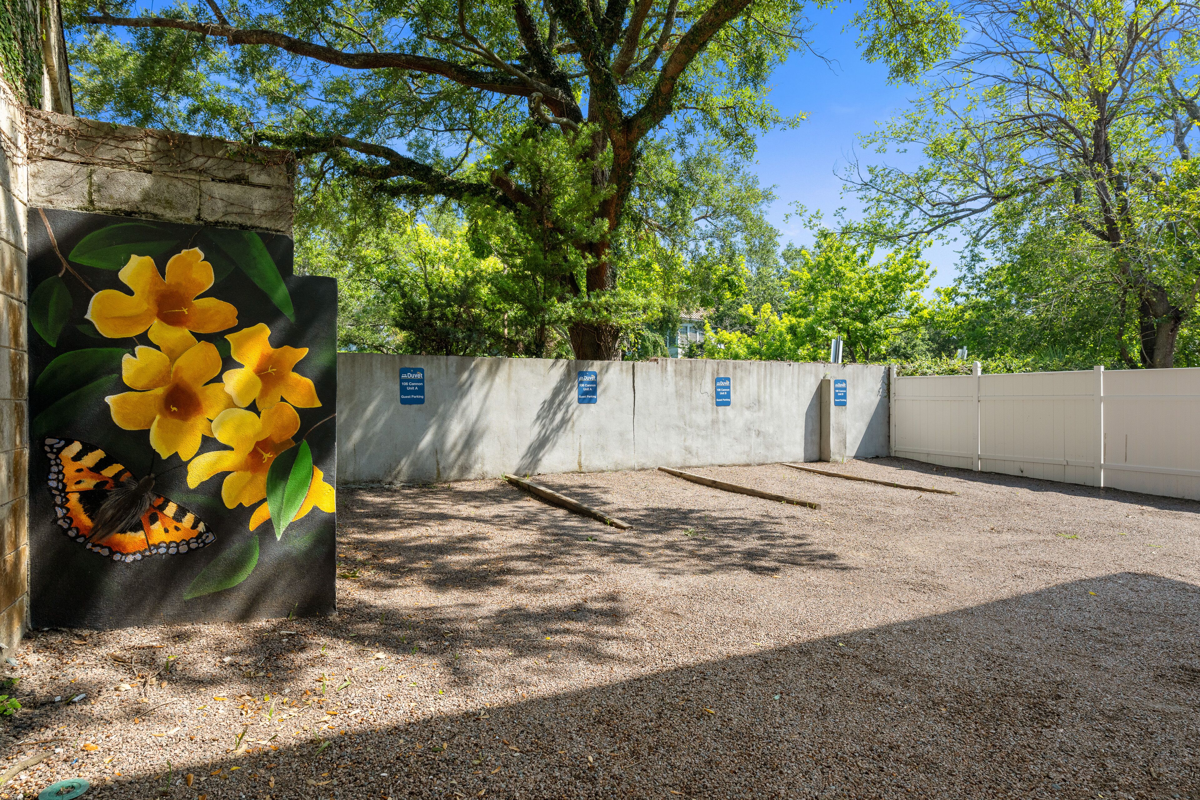 A parking area with a concrete wall and a mural of yellow flowers and a butterfly.