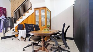 A conference room with a round table, office chairs, a wooden cabinet, and a staircase. - OYO 91322 Jawara Guest House Syariah (Bandung)