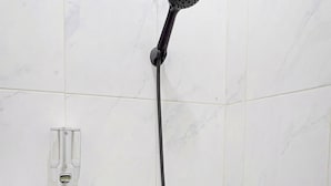 A shower with a handheld showerhead mounted on a wall. - OYO 91322 Jawara Guest House Syariah (Bandung)