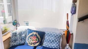 A cozy seating area with a window, a wooden bench, and a colorful umbrella.