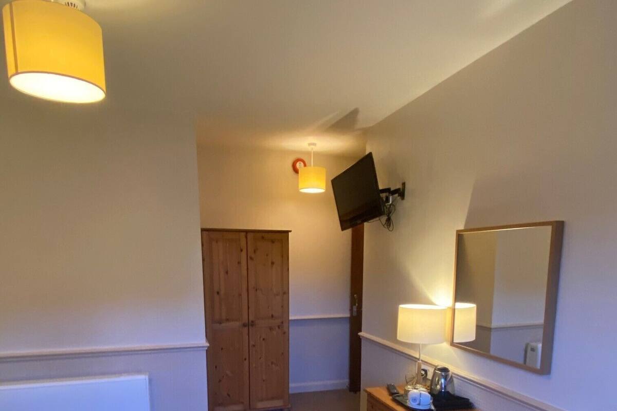 A bedroom with a bed, a desk, a chair, a television, and a wardrobe.