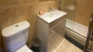 Un baño moderno con inodoro, lavamanos y ducha envuelta en vidrio.