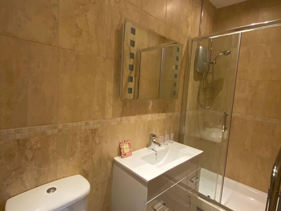 Un baño moderno con inodoro, lavamanos y ducha envuelta en vidrio.