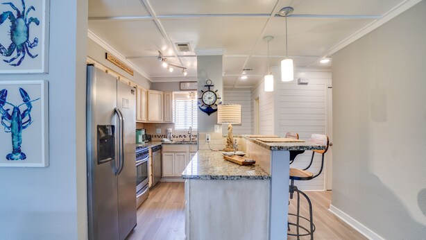 A modern kitchen with a central island, stainless steel appliances, and pendant lighting. - Beachwalk Resort by Panhandle Getaways (Panama City Beach)