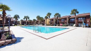 A swimming pool surrounded by palm trees and a row of multi-story buildings with balconies. - Beachwalk Resort by Panhandle Getaways (Panama City Beach)