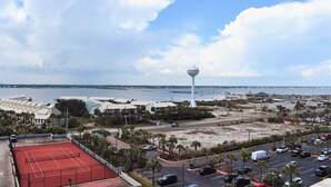Een kustgezicht met een tennisbaan, parkeerplaats en een opvallende witte toren.