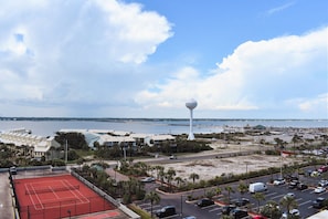 A coastal view with a tennis court, parking area, and a prominent white tower. - Pristine, Family-friendly condo. Spectactular Gulf Views! (Navarre)