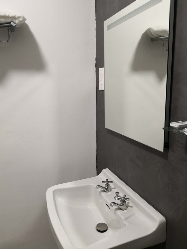 A bathroom with a white sink, a mirror, and a towel rack. - Quiet town center, sea view, private parking, 250 m from the beach (Ajaccio)