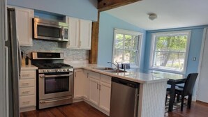 A kitchen with white cabinets, stainless steel appliances, a dishwasher, and a wooden floor. - 3 bedroom home steps away from beach/lake (Petersburg)