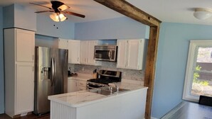 A kitchen with white cabinets, a stainless steel refrigerator, a microwave, and a stove. - 3 bedroom home steps away from beach/lake (Petersburg)