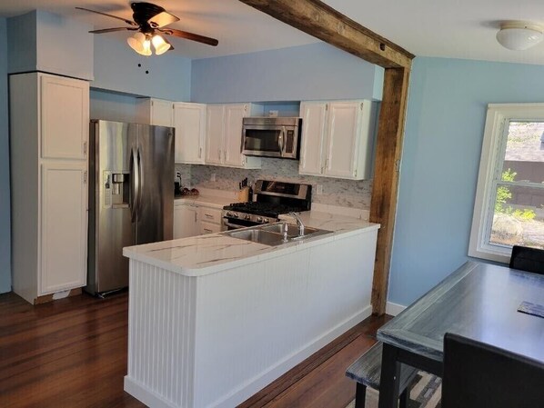 A kitchen with white cabinets, a stainless steel refrigerator, a microwave, and a stove.