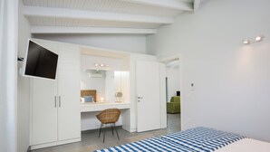 Quarto com cama, escrivaninha, cadeira, guarda-roupa e televisão na parede.