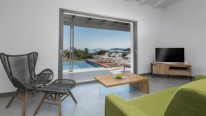 Sala de estar moderna com vista para a piscina, televisão de tela plana e sofá verde.