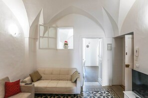 A living room with a sofa, a TV, and a patterned floor. - Casa Vacanza Del Cuore 1 (Gallipoli)