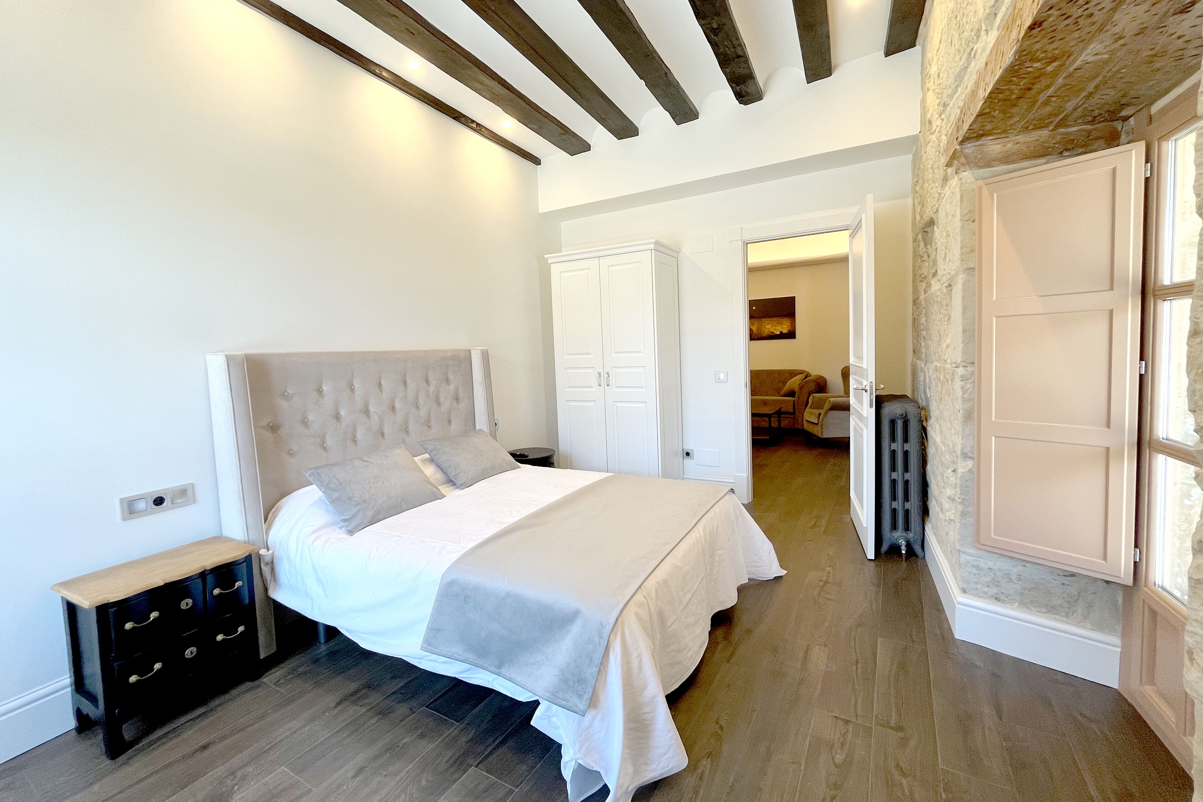 A bedroom with a bed, a nightstand, a wardrobe, and a radiator.