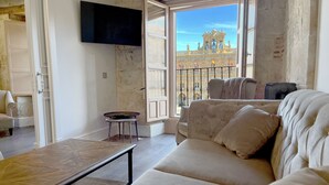 Un salon spacieux doté d’une grande fenêtre donnant sur un bâtiment historique.