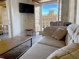 A spacious living room with a large window offering a view of a historic building.