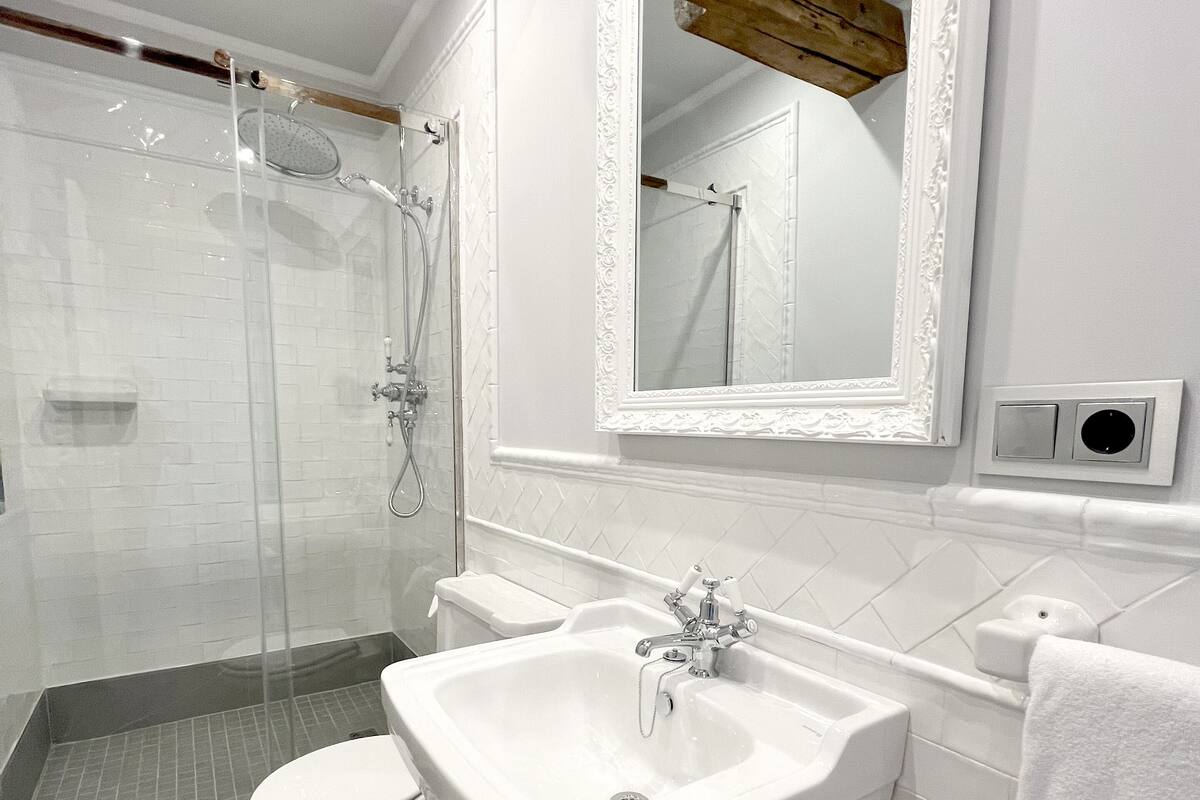 A modern bathroom with a glass-enclosed shower, a white sink, and a large mirror.