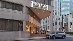 Un hotel Staybridge Suites con una fachada moderna, grandes ventanales y una entrada destacada.