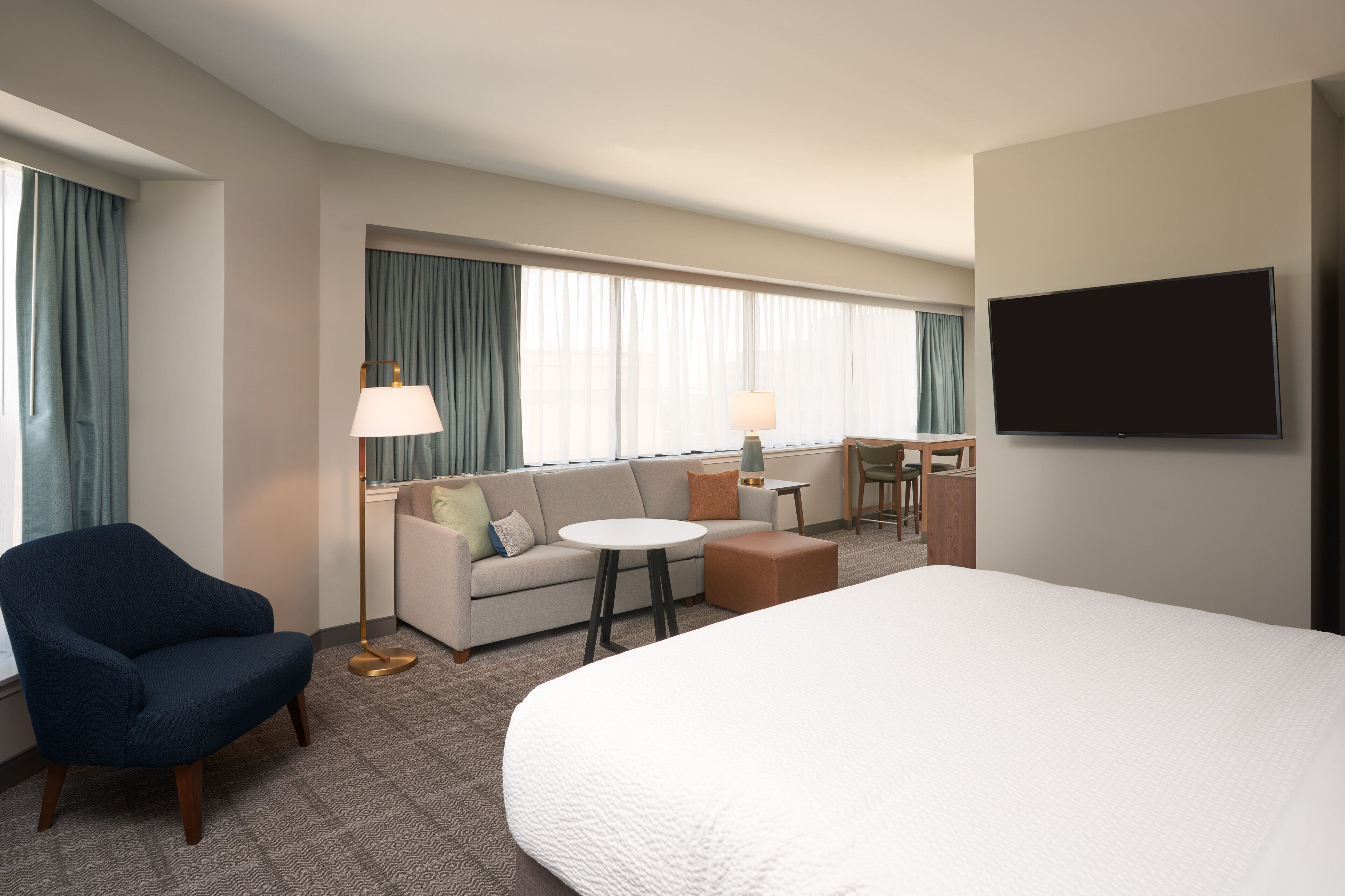 Una habitación de hotel con una cama grande, un sofá, una silla, un escritorio y un televisor.