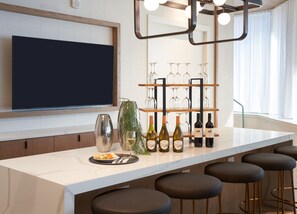A modern kitchen with a large island, wine bottles, and glasses on shelves. - Staybridge Suites Wilmington Downtown by IHG (Wilmington)