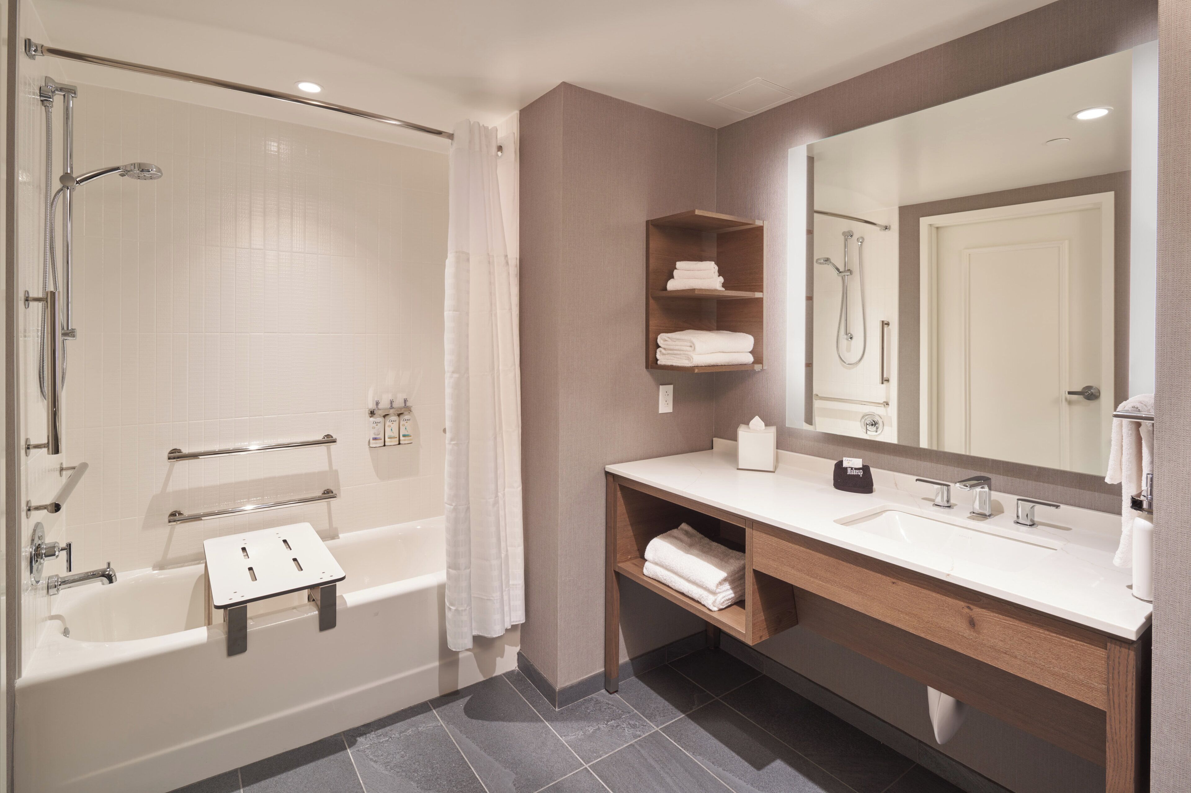 A modern bathroom with a bathtub, shower, vanity, and a large mirror.