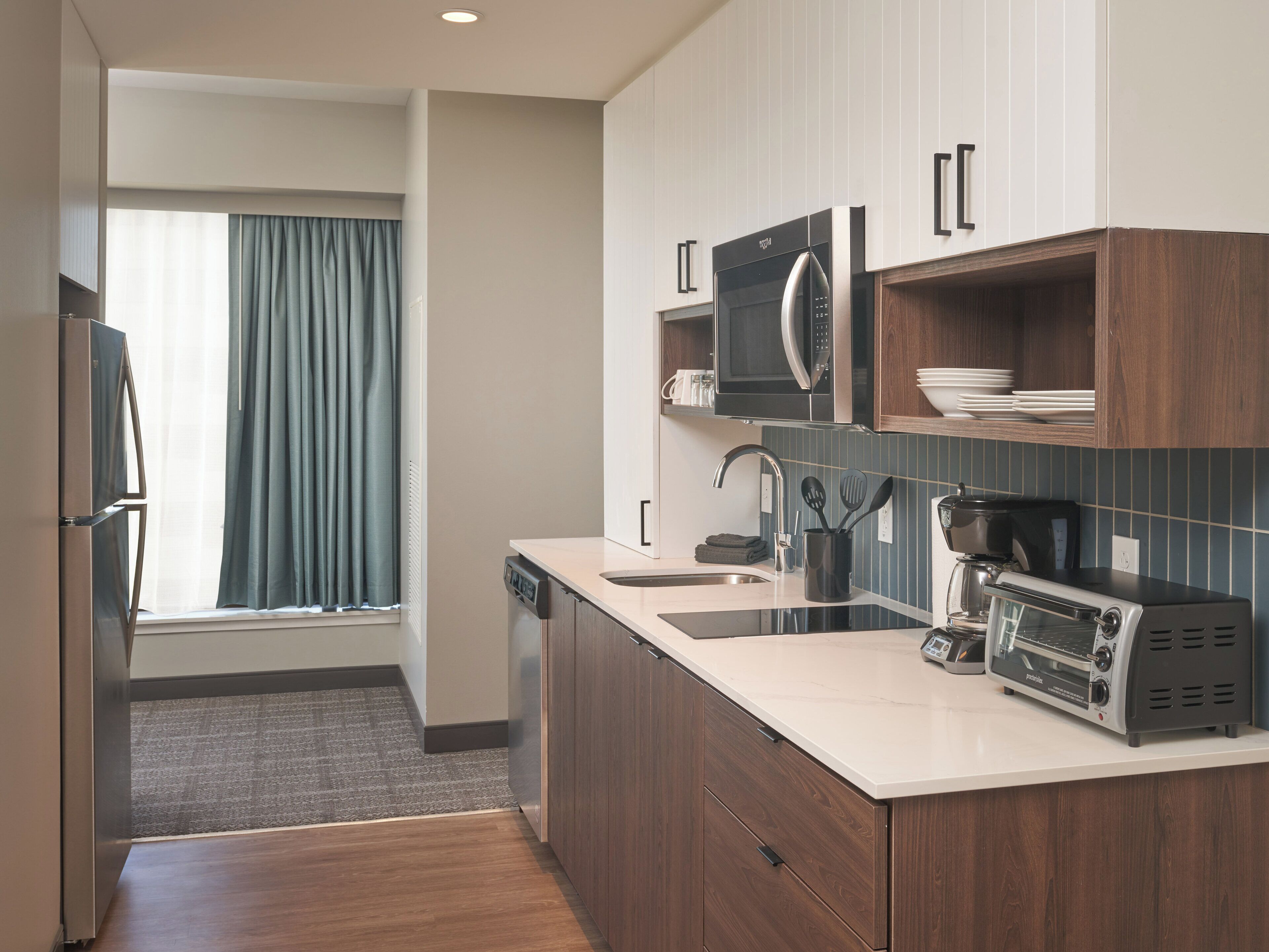 A modern kitchen with a dishwasher, microwave, toaster, and a sink.