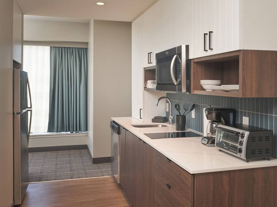 A modern kitchen with a dishwasher, microwave, toaster, and a sink.
