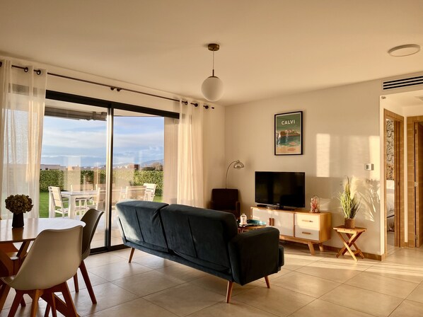A modern living room with a sofa, TV, and dining area.