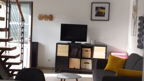 Una sala de estar moderna con una escalera, un televisor de pantalla plana y un sofá con cojines amarillos.