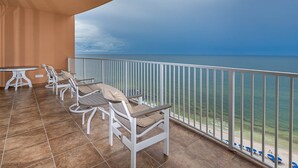 A balcony with white chairs and a table, overlooking a beach and the ocean. - Beach & Lazy River Escape Phoenix Orange Beach 1204 (Orange Beach)