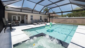 Ein überdachter Poolbereich im Freien mit Liegestühlen, einem Whirlpool und einer Terrasse.