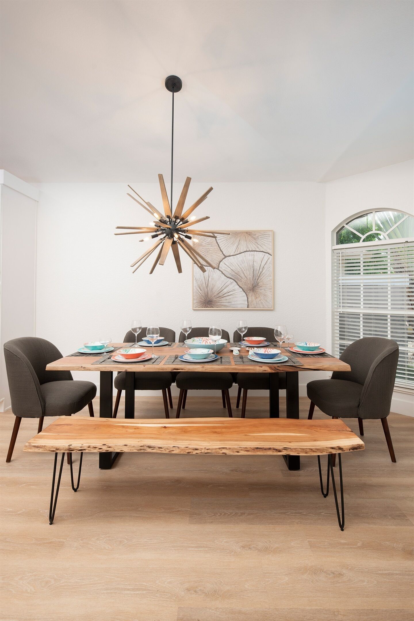Een eetruimte met een houten tafel, zwarte stoelen en een moderne hanglamp.