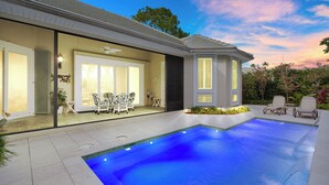 Une maison moderne dotée d’une piscine, d’un espace salon extérieur et d’un patio bien éclairé.