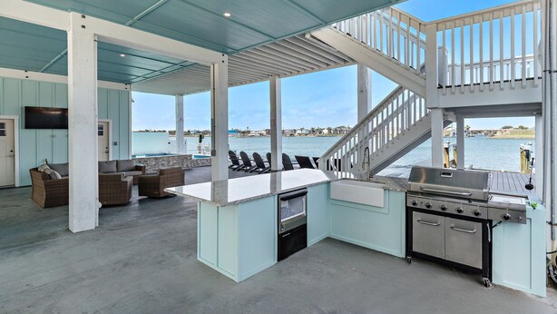 Ein Outdoor-Kochbereich mit Grill, Sitzgelegenheit und Blick auf das Wasser.