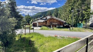 Een houten lodge met een schuin dak, omringd door weelderige begroeiing en bergen.