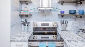 Een moderne keuken met een inbouwoven, roestvrijstalen aanrechtbladen en een centraal afzuigsysteem.