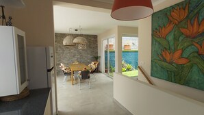 Una cocina moderna con comedor, pared de piedra y vistas a una piscina.