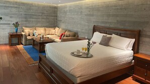 Une chambre moderne avec un grand lit, un canapé et une petite table sur laquelle se trouve un plateau avec des éléments pour le petit-déjeuner.