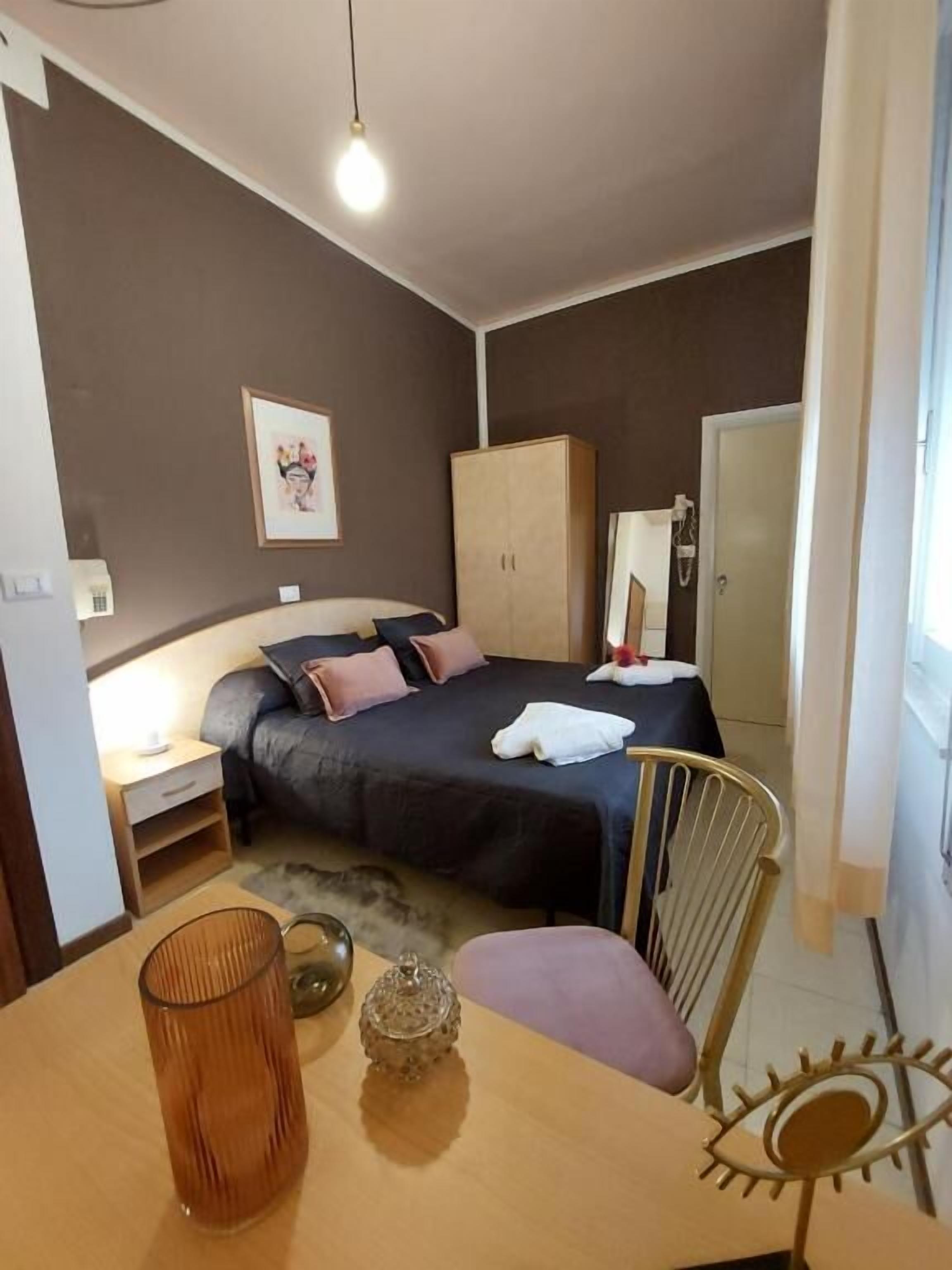 A bedroom with a bed, bedside table, lamp, wardrobe, and a chair.