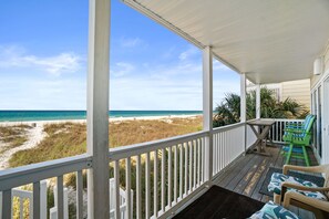 A covered porch with a view of the beach, wooden deck, and outdoor seating. - Harbur Arms by Panhandle Getaways (Panama City Beach)