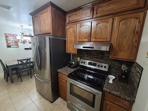A kitchen with wooden cabinets, a stainless steel refrigerator, a built-in oven, and a granite countertop.