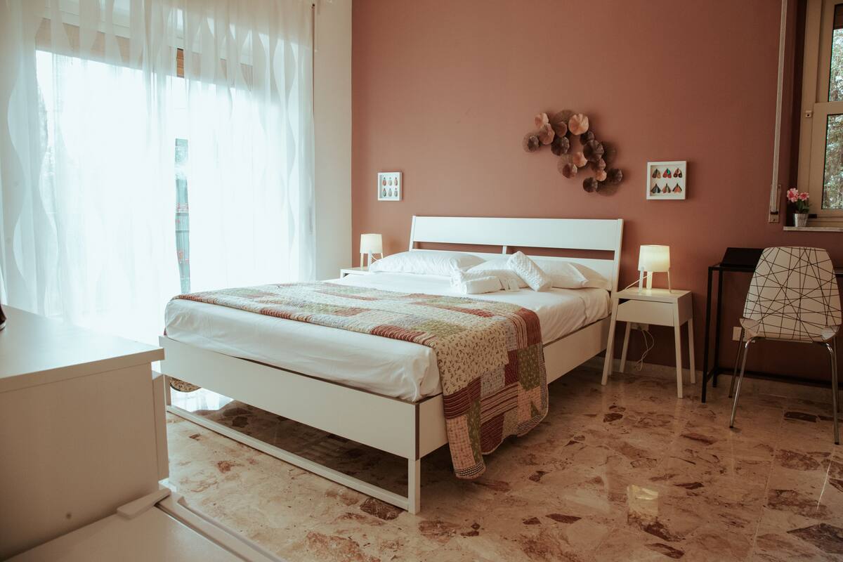 A bedroom with a bed, bedside tables, a chair, and a window with curtains.