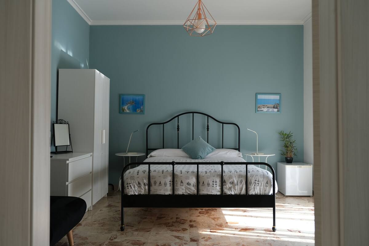 A bedroom with a bed, bedside tables, a wardrobe, and a desk.