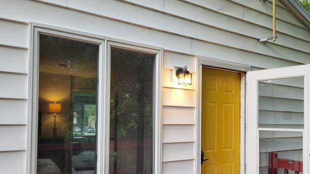 A house with a yellow door and a window with a lamp outside. - Chesapeake Bay Loft Retreat, Walk to Water, Sleeps 2,  20 Min to Annapolis (Deale)