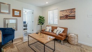 A living room with a brown leather sofa, a blue armchair, and a wooden coffee table.