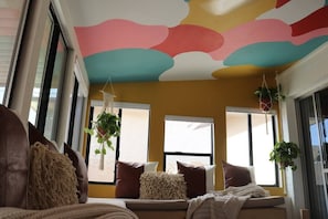 A cozy living room with a sofa, cushions, and hanging plants. - The Desert House Charming w/ Hot Tub (Scottsdale)