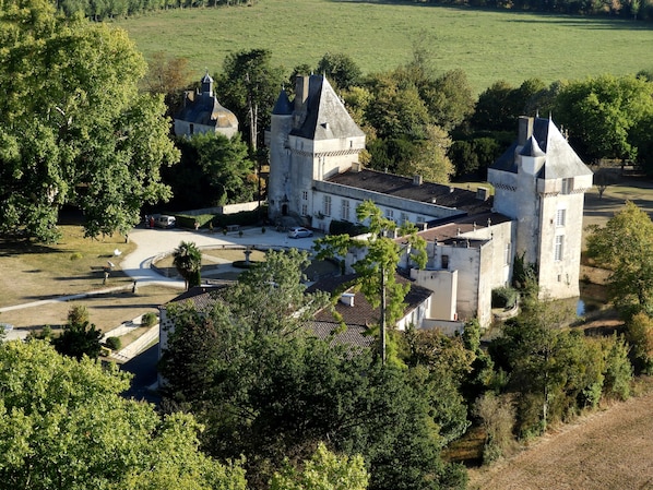 Eine große Burg mit mehreren Türmen, umgeben von üppigem Grün und einem gepflegten Rasen.