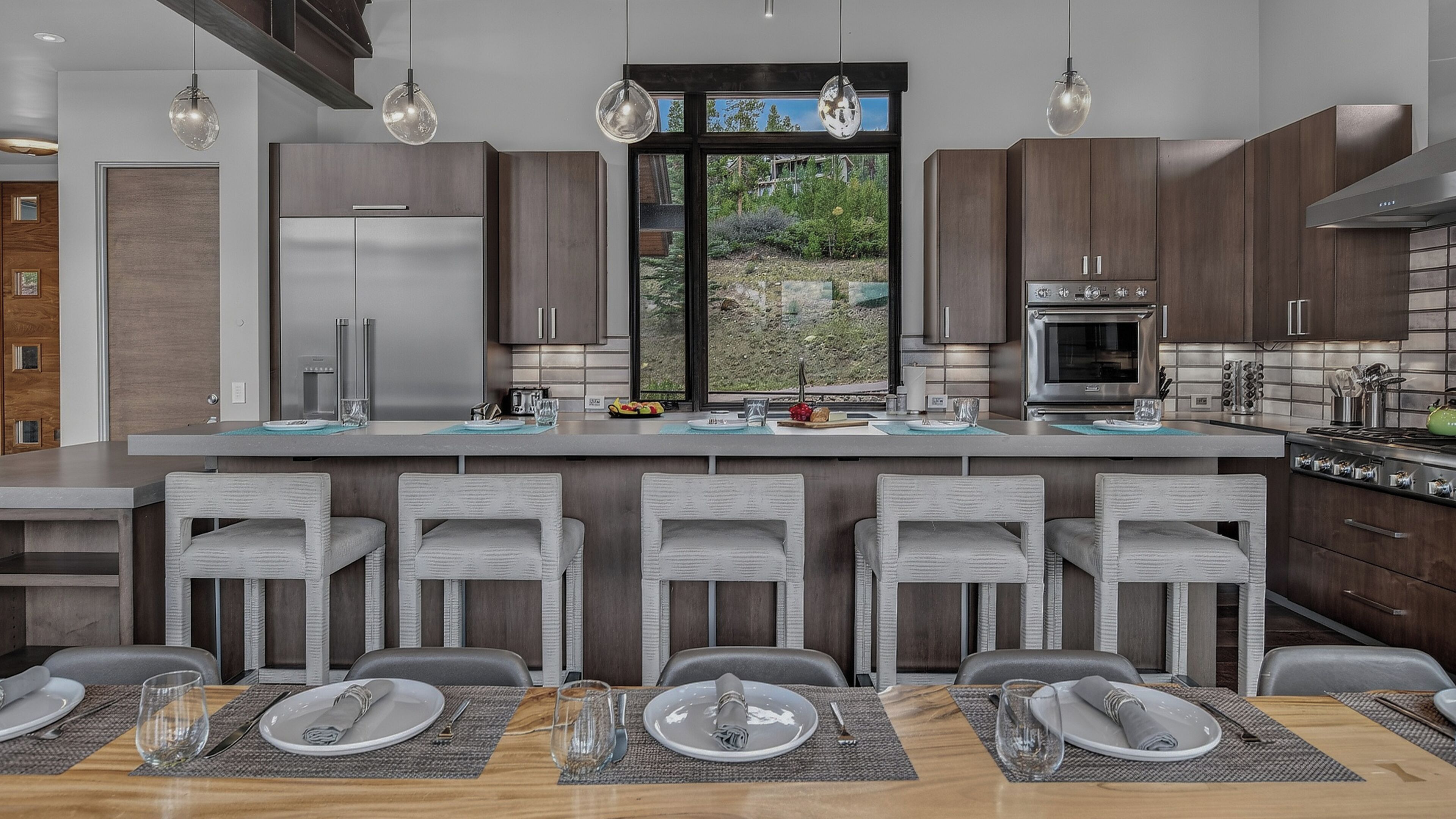 A modern kitchen with a large island, bar stools, and a dining area.